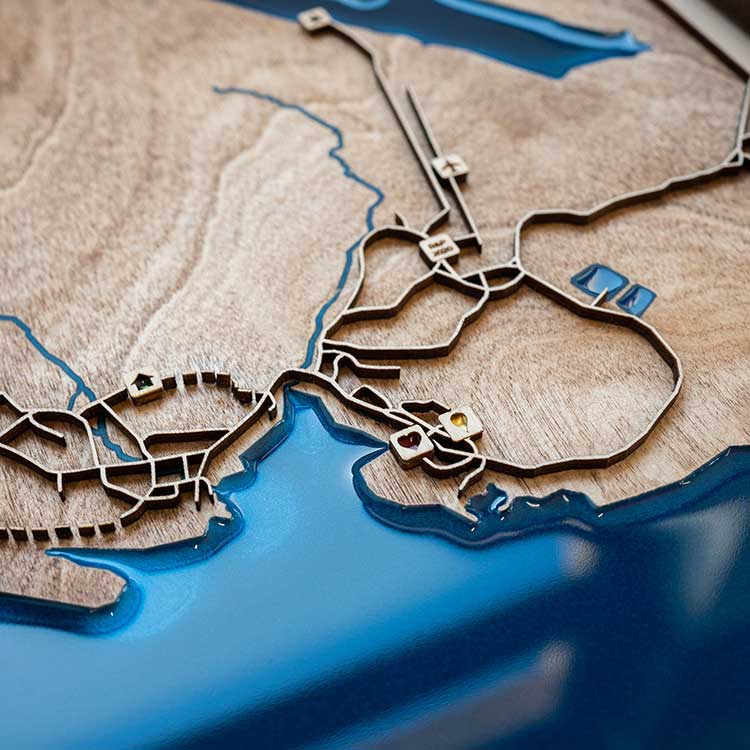 Wooden map with blue resin finish of a coastal area.